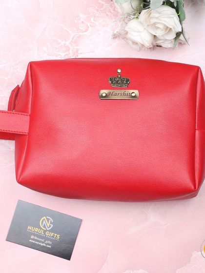 The personalized leather pouch is also available in a vibrant red color, shown here with a custom name and crown charm.