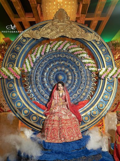 A breathtaking bridal entry shot, with the bride seated on a magnificent, throne-like structure, surrounded by smoke. This is a portrait of pure royalty.