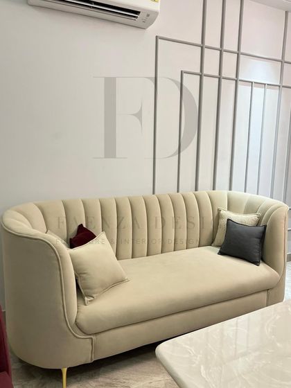 A close-up of the channel-tufted sofa in a soft beige fabric. The elegant curves and plush cushions create a piece that is both visually appealing and exceptionally comfortable.