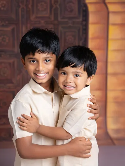 A warm hug between two brothers. Dressed in matching traditional outfits, their smiles and embrace show the strong connection they share.