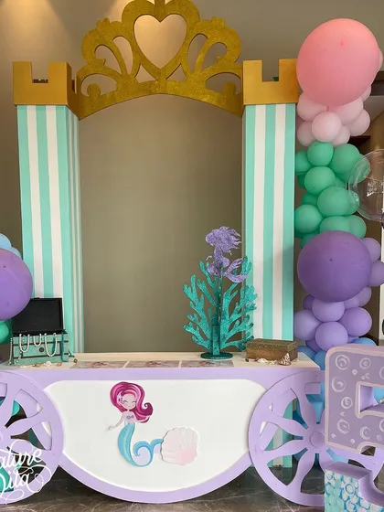 A mermaid-themed carriage cart, decorated with a castle-like top and a large number '5', serving as a fun station for activities or treats.