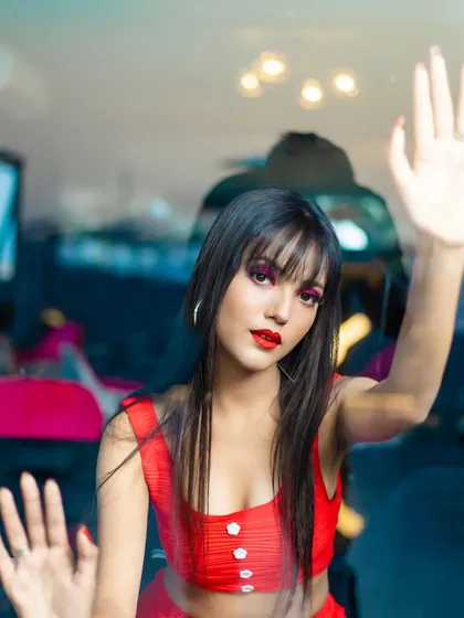 A close-up from a modern commercial shoot. The focus here is on the clean, bold makeup with sharp red eyeshadow and a matching lip, paired with sleek hair and bangs for a contemporary and chic vibe.