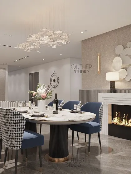 A home should tell the story of who we are. This dining area is set by a cozy fireplace, with houndstooth and blue chairs around an oval table, creating a warm and inviting space for gatherings.