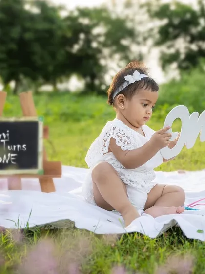 "Charvi Turns One." This outdoor setup with a mini chalkboard and "one" sign is a sweet way to announce and celebrate a first birthday.