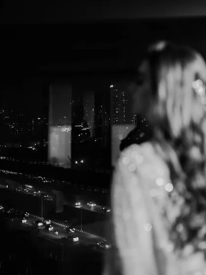 A bride looking out over the city lights at night. This black and white photo is moody, atmospheric, and full of emotion. It’s a quiet moment of reflection before the party begins.