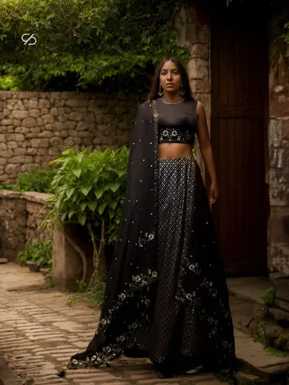 For the modern woman who embraces bold elegance, this black lehenga is a statement of sophisticated glamour. The design features intricate silver embellishments and a contemporary silhouette, perfect for a sangeet night or a grand reception.