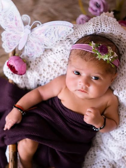 Wide awake and curious. This beautiful newborn girl with a butterfly prop looks right at the camera, showing her alert and sweet personality.