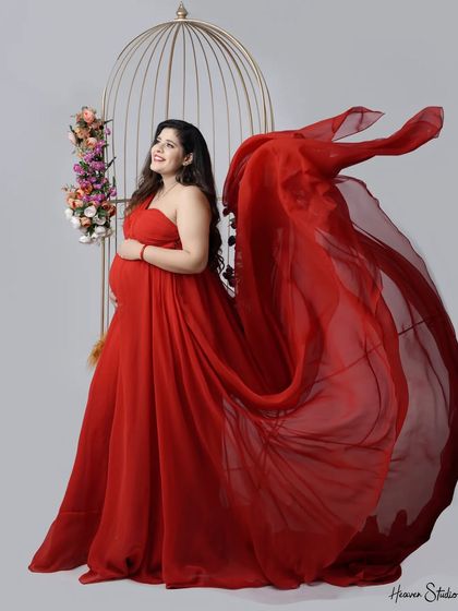 The power and beauty of a mother-to-be, captured in a radiant red gown. The flowing fabric and joyful expression make this a standout studio portrait.