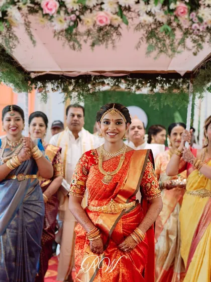 A radiant bride making her entrance under a floral canopy held by her family, a beautiful tradition in South Indian weddings.