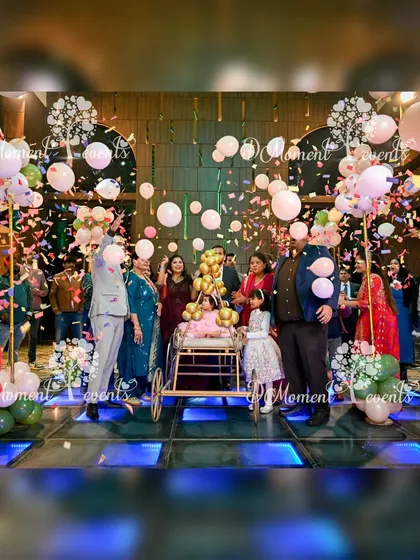 A magical moment captured during a baby's entrance at a teddy bear party. The baby is in a decorative cart while confetti and balloons rain down on the LED dance floor.