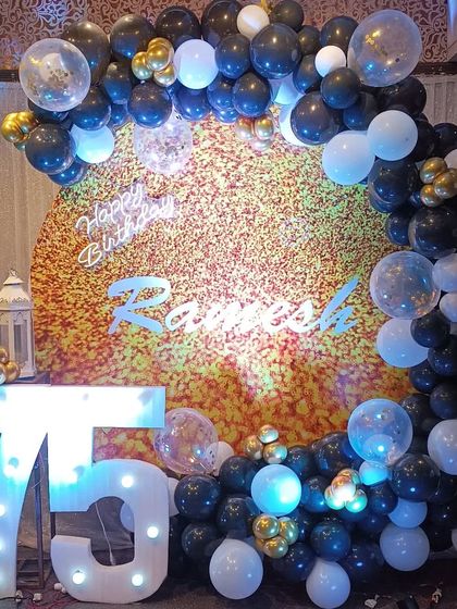 For this 75th birthday, we used a textured gold backdrop with a circular balloon arch in black, white, and gold. The large marquee numbers and confetti balloons add a touch of modern celebration to the classic color scheme.