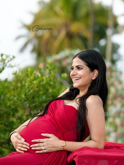 A joyful, candid shot of a mother-to-be in a red fabric wrap, enjoying the moment in our private outdoor location.