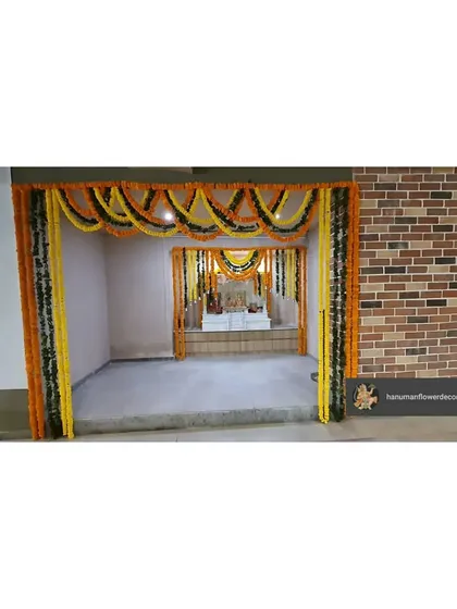 An entrance to a pooja room within a corporate building, decorated with traditional marigold and mango leaf garlands. This creates a clear and auspicious entryway for prayer.