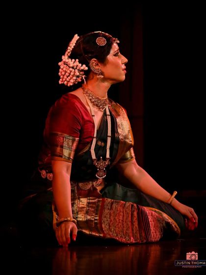 A seated posture, or 'mandi', from a traditional piece. Even in moments of stillness, the dancer's form communicates a story and emotion.