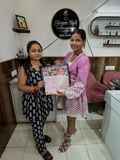 Another successful student receives her professional nail technician certificate along with her completed art portfolio.