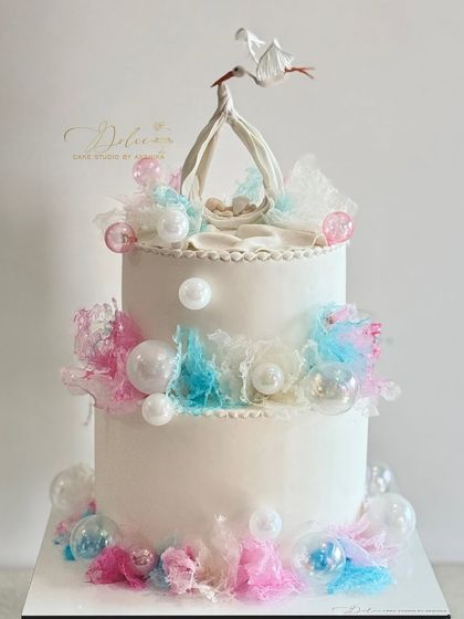 A classic "stork delivery" cake for a baby shower. The design uses pulled sugar work and delicate textures to create a light, airy feel.