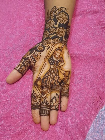 A full-palm design featuring a woman holding a dandiya stick, perfect for Navratri celebrations. The wrist is adorned with a dense floral pattern.