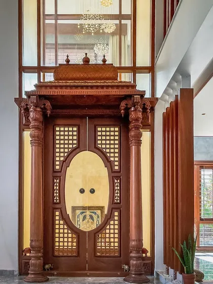 We honor traditional craftsmanship in our modern designs. This ornate Pooja room entrance features intricately carved wooden pillars and doors, creating a serene and sacred space within the home that reflects our client's heritage.