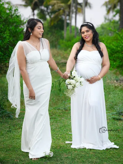 A beautiful outdoor portrait of two friends or sisters in matching white gowns, celebrating the journey of motherhood together.