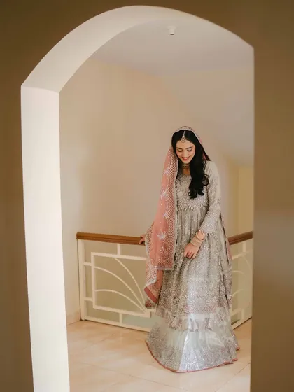 An elegant portrait of the bride on her engagement day, framed by an archway in her home, capturing her grace and beautiful attire.