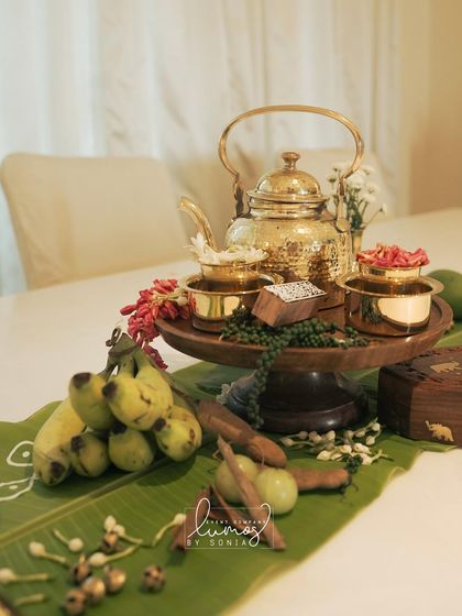 A beautiful brass tea set and other traditional items arranged on a banana leaf as part of an antique-themed decor.