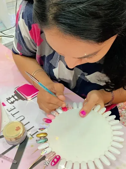 This student is practicing her nail art on a color wheel, surrounded by a variety of polishes and tools.