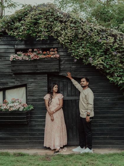 Another shot of the couple by the rustic cabin, this time with the groom pointing up at the ivy-covered roof.