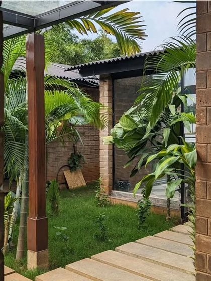 A view into a private courtyard where a stone path cuts through a small lawn. The combination of brick, stone, and turf creates a space that is both structured and soft.