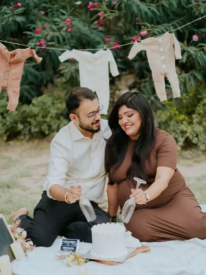 Getting ready for the big reveal. This outdoor picnic setup with a cake and baby clothesline creates a fun and festive atmosphere for a gender reveal photoshoot.