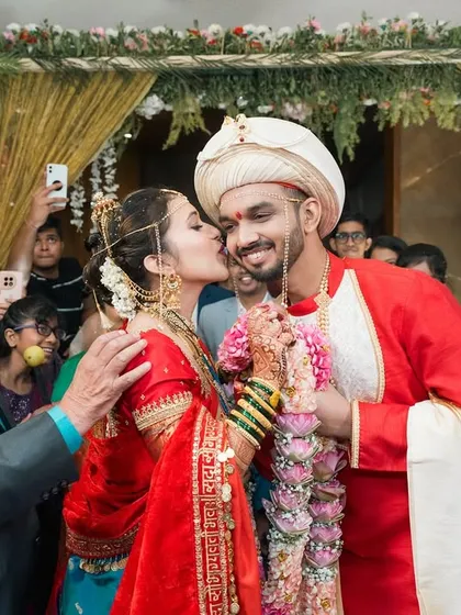 A sweet kiss from the bride amidst the joyful chaos of the wedding rituals. A perfect candid moment surrounded by smiling family.