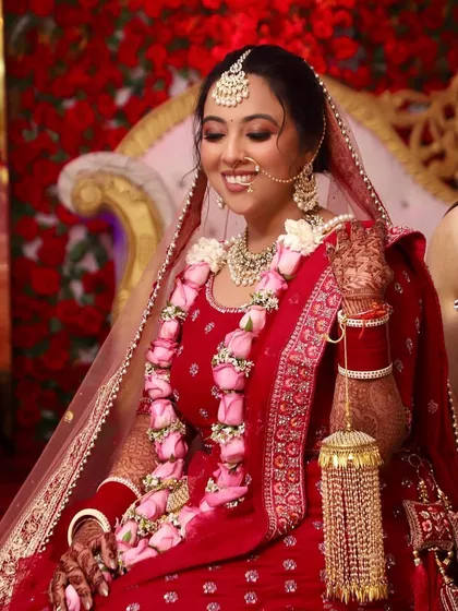 Shreya looks absolutely radiant on her wedding day. Her classic red lehenga is paired with a soft, glowing makeup look and a beautiful rose garland, capturing the joy of the moment.