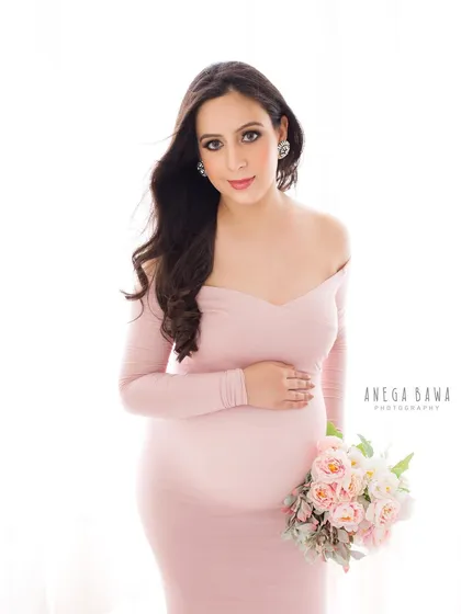 Soft, romantic, and feminine. This portrait in a pink off-the-shoulder gown, complete with a bouquet of peonies, creates a delicate and timeless image of motherhood.