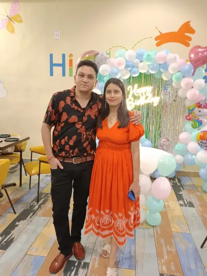 A happy couple posing against a pastel balloon arch. Parents deserve to have a great time and make memories too.