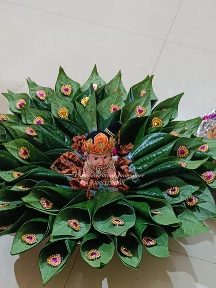 For a unique and eco-friendly option, I create beautiful arrangements using paan leaves. This platter features a doll seated on a bed of betel leaves, perfect for a traditional and natural theme.