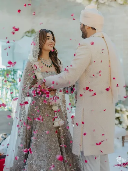 The couple shares a look during their ceremony, surrounded by a sea of white florals and elegant decor, creating a serene and pure ambiance.