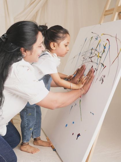 Art creating art. A mother and her daughter make their mark on a canvas, their hands side-by-side. This interactive studio session is a beautiful way to document shared activities and creative bonds.