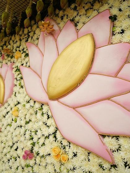 A close-up of the custom lotus cutouts against a dense wall of white flowers. These small, thoughtful details are central to our design philosophy, adding depth and personality to the event decor.