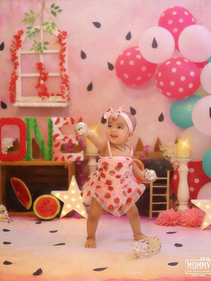 Dancing with joy! This little one is having the best time at her watermelon-themed party, surrounded by pink and green balloons and adorable props.