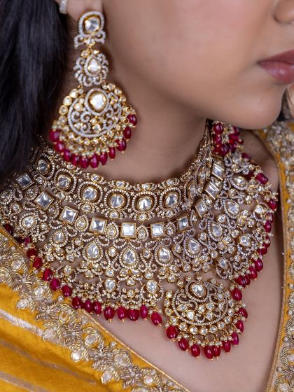 A detailed close-up of our red Kundan bridal choker. The image shows the intricate setting of the stones and the rich color of the ruby beads, perfect for a traditional bride.