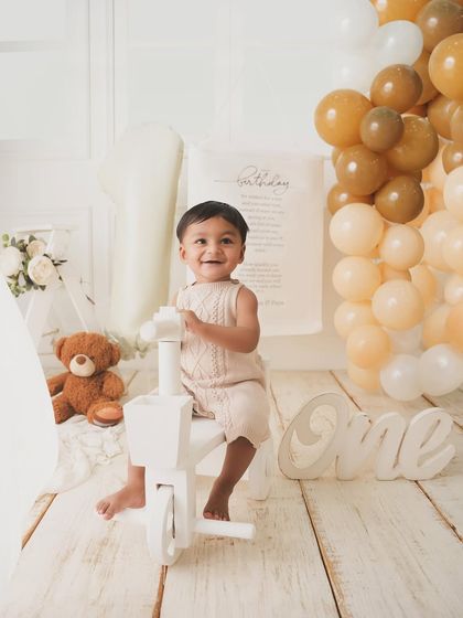 The birthday boy enjoys a ride on his little white tricycle, smiling from ear to ear.