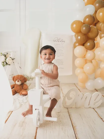 The birthday boy enjoys a ride on his little white tricycle, smiling from ear to ear.