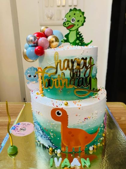 A two-tier dinosaur-themed cake with cute, colorful dinosaurs for a prehistoric party.