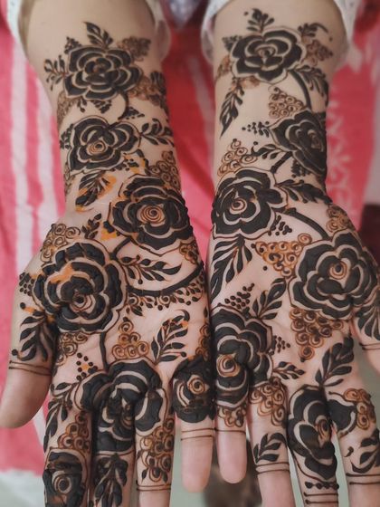 A full-hand design featuring bold, black-stain style roses. The dark, prominent flowers create a powerful and dramatic look, perfect for someone who loves bold mehendi art.