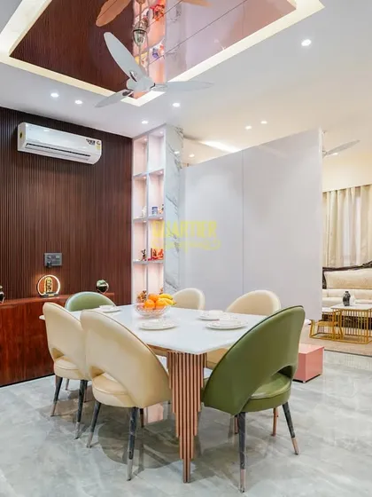 A view of the dining area in the Sector 22, Noida home, showing the custom partition that provides a subtle separation from the living space. The mix of green and beige chairs complements the adjacent kitchen's color scheme.