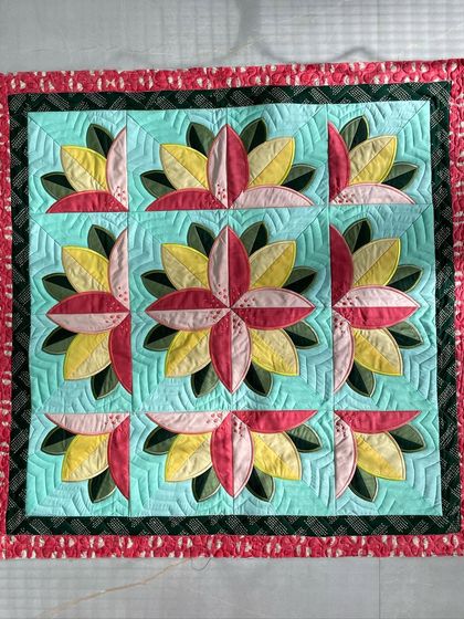 A "Big Bloom" wall quilt featuring stylized lotus-like flowers, with intricate ruler work quilting in the background.