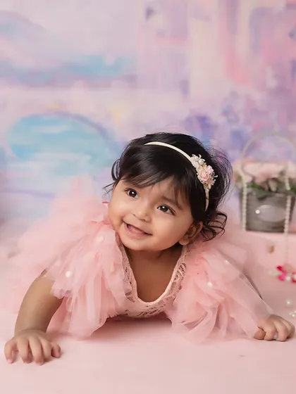 Looking up with a sweet, cheerful expression. The lighting and setup are designed to keep the focus on the baby.
