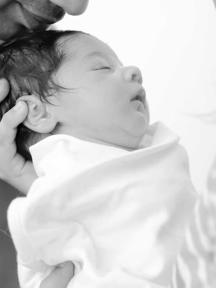 A close-up of a sleeping newborn, safe in their father's hands. These are the details we never want you to forget.