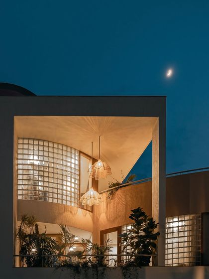 The exterior view of the home at dusk reveals how the design glows from within. The glass block walls, which provide privacy during the day, become luminous features at night, showcasing the home's warm and inviting interior.