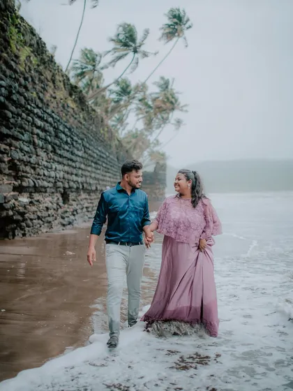 A romantic walk along the shoreline during a monsoon pre-wedding shoot. The misty weather and waves create a moody and dramatic atmosphere for your photos.