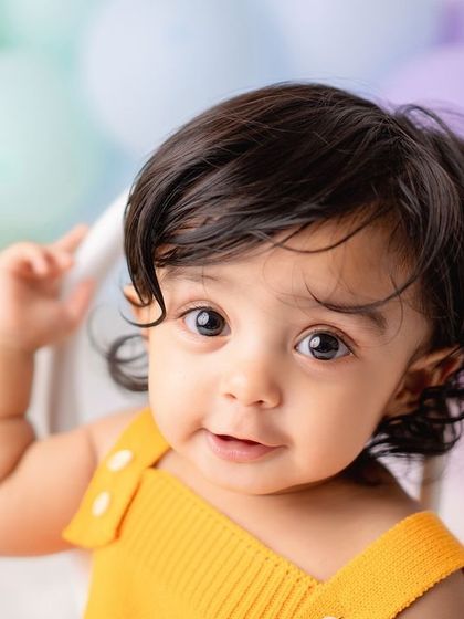 A sweet close-up of a baby girl in a bright yellow outfit, part of a pastel rainbow-themed session.